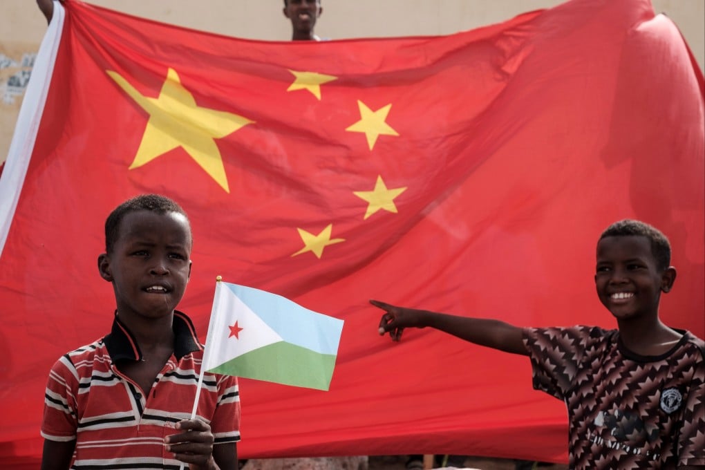 A boy holds a Djiboutian flag in front of a Chinese flag as he waits for Djibouti’s President Ismail Omar Guellehas to conduct the launching ceremony of a 1,000-unit housing project with Chinese financial support in Djibouti, on July 4, 2018. Photo: AFP