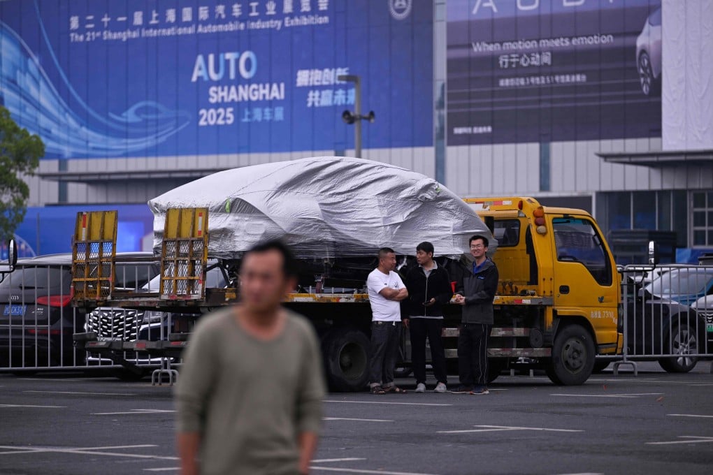 Workers stand by a car being delivered to the National Exhibition and Convention Center ahead of the Shanghai Auto Show in Shanghai on April 22, 2025. Photo: AFP