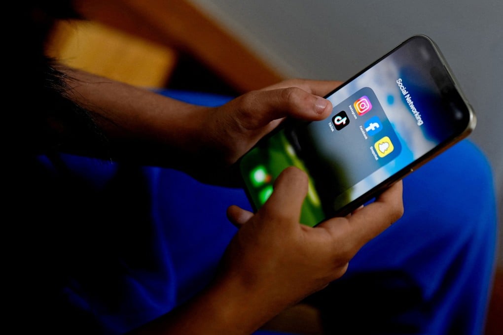 A student looks at social media apps on her mobile phone. Regulators the world over are wrestling with how to keep children safe online. Photo: Reuters