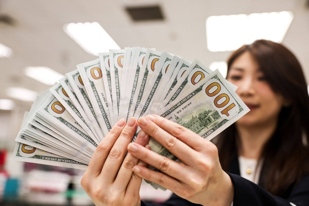 A bank employee poses with US$100 notes in Taipei on May 6, 2025. Photo: AFP