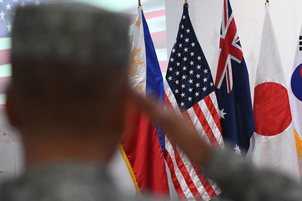 A Philippine Marine salutes in front of US, Philippine, Australia, and Japan flags during joint military drills in October 2024. Photo: AFP