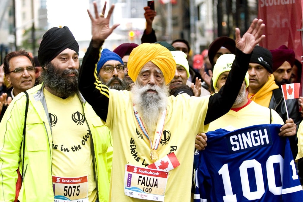 Fauja Singh (centre), then 100, celebrates after completing the Toronto Waterfront Marathon in 2011. Photo: AP
