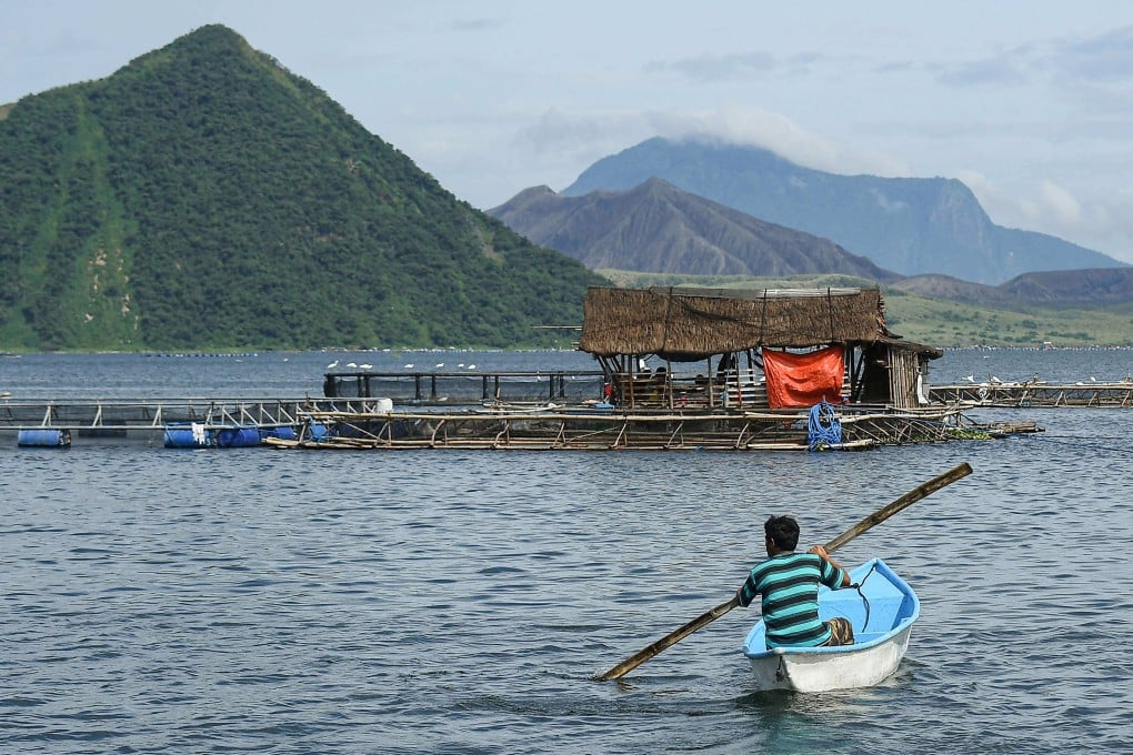 A fisherman rows his boat near fish cages on Taal Lake off Laurel municipality, at the foot of the Taal Volcano, on July 10. Photo: AFP