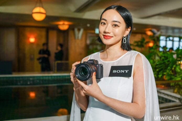 女性攝影師手持索尼相機微笑展示.