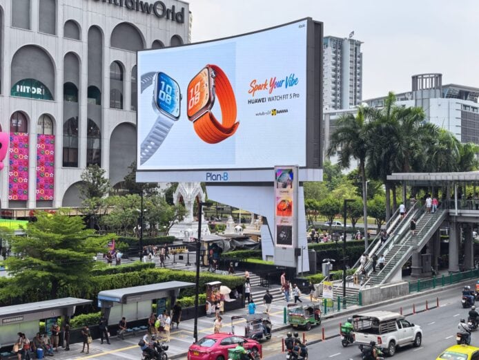 華為智能手錶FIT 5和Pro款在戶外廣告牌展示,吸引眾多行人和車輛經過,彰顯其時尚與科技結合的特色。.