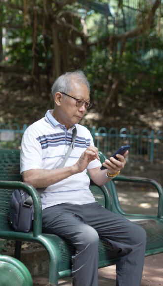 長者在公園使用手機.