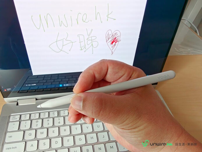 手持YOGA筆在筆記本前.