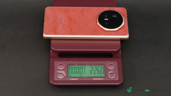 紅色Honor Magic V6手機放在電子秤上.