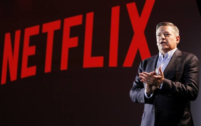 Netflix CEO 發表演說，背景有大字LOGO.