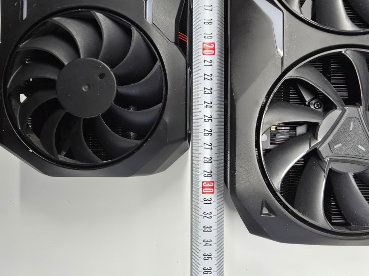 Two large computer cooling fans next to a measuring tape indicating size comparison.