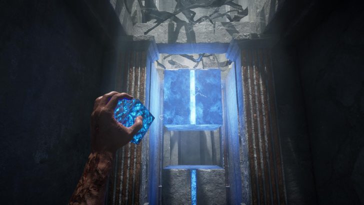 Hand holding glowing blue crystal in ancient stone chamber with blue-lit cube.