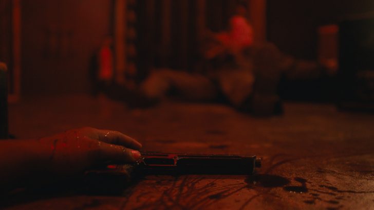 Dead Reset, Bloody hand gripping a handgun on the floor with a blurred background figure.