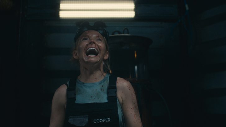 Dead Reset, Person in a dimly lit room, looking upwards with a determined expression, wearing a vest labeled COOPER.