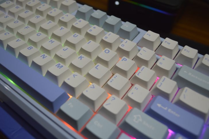 Close-up of a mechanical keyboard with RGB lighting, featuring white and blue keycaps.