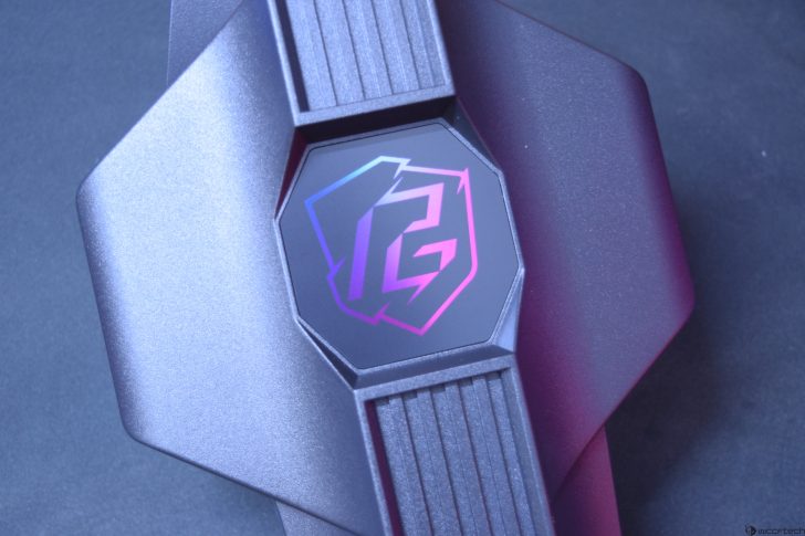 Close-up of a futuristic black device with a colorful logo on its center, displayed against a dark background.