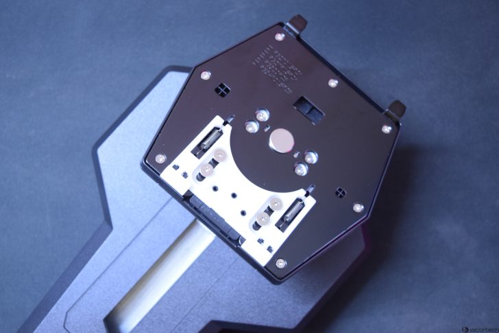 Close-up of a device component on a dark surface, featuring screws and springs.