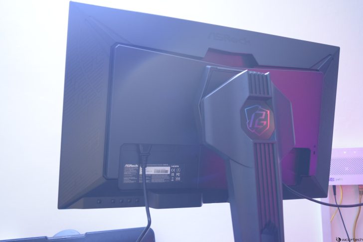 Back view of ASRock gaming monitor with branded stand and HDMI connection cable.