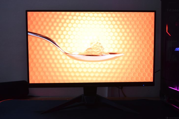 Monitor displaying honey on a spoon with a hexagonal pattern background.