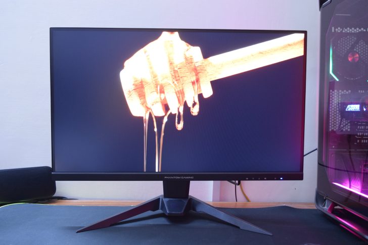 Gaming monitor displaying a honey dipper with dripping honey, beside a gaming PC setup.