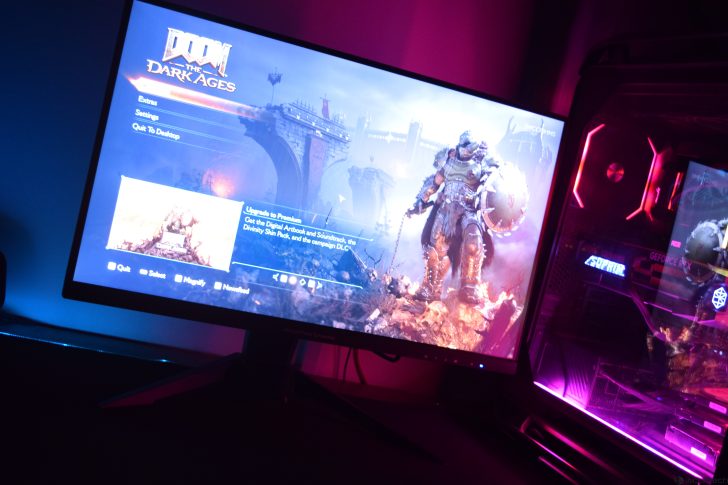 Gaming setup with monitor displaying Doom: The Dark Ages menu in vibrant lighting.