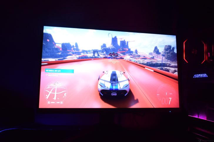 Racing game on a PC screen with a white sports car on a vibrant orange track.