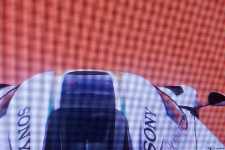 Race car on a red background, top view, with sponsor logos visible.