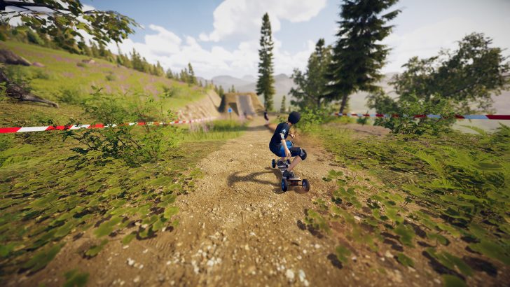 Descenders Next Person mountainboarding on a scenic dirt trail with trees and hills in the background.