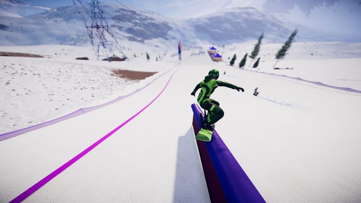 Snowboarder in green gear grinding a rail on a snowy slope with mountains in the background.