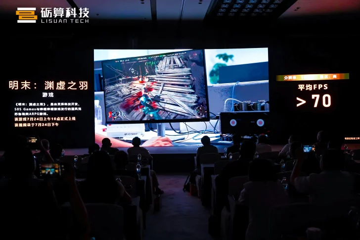 Audience watching a gaming presentation on stage with a large screen display.