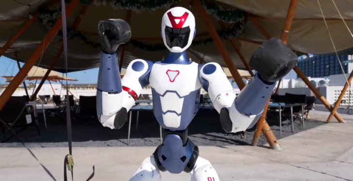 Robotic humanoid raises fists, showcasing advanced technology in an outdoor setting.
