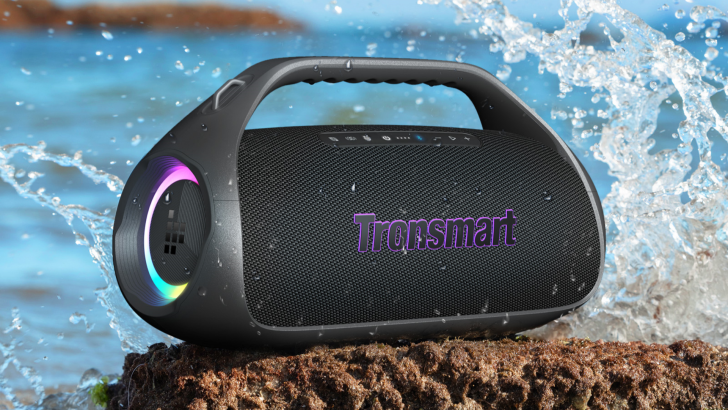Portable waterproof speaker with handle on rock, splashing water background.