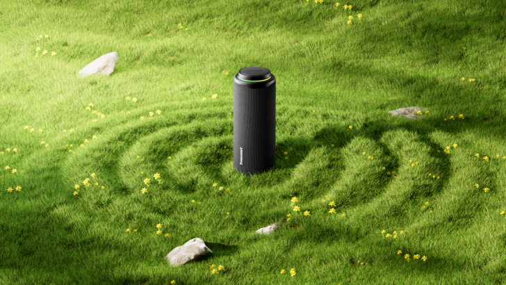 Portable speaker in lush green grass with scattered yellow flowers, radiating sound waves.