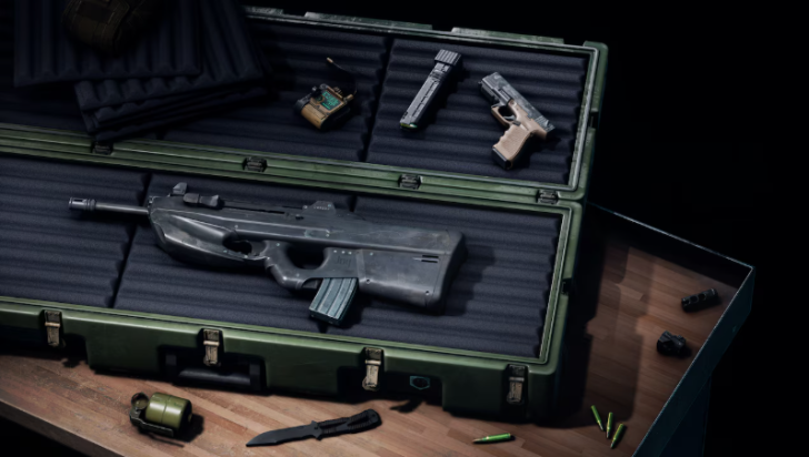 Rifle and accessories in a green case on a wooden table, including pistols and a knife.