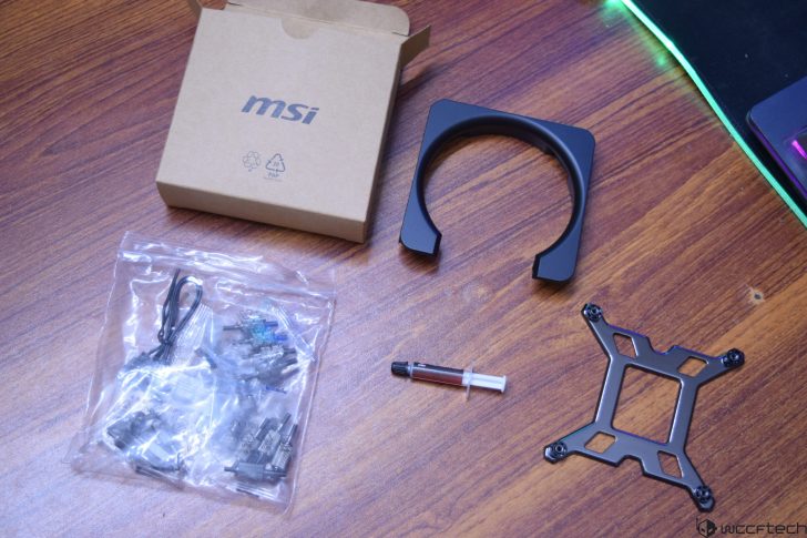 MSI motherboard accessories kit on wooden table, includes bracket and thermal paste.