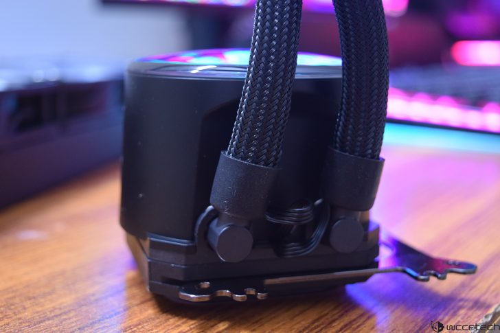 Close-up of a computer liquid cooling system with braided tubing and RGB lighting.