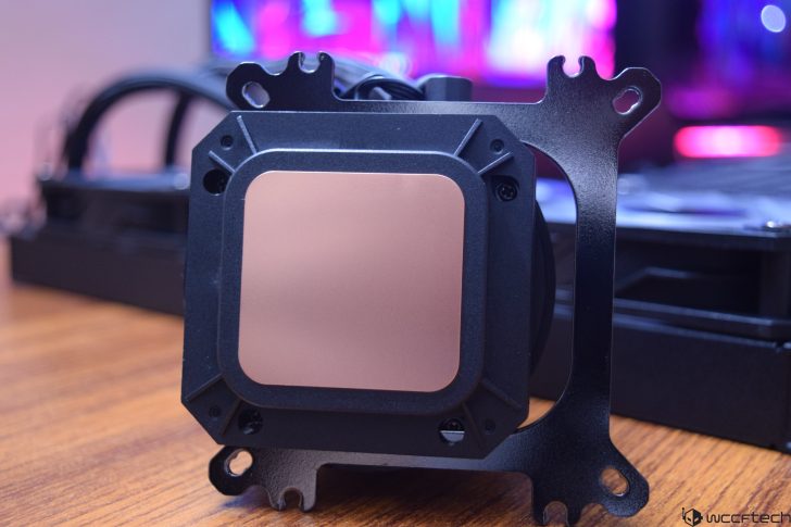Close-up of CPU water block with copper base on a wooden desk.