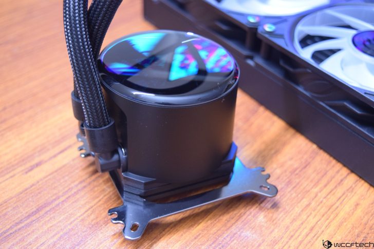 Close-up of a CPU liquid cooler with cables on a wooden surface.