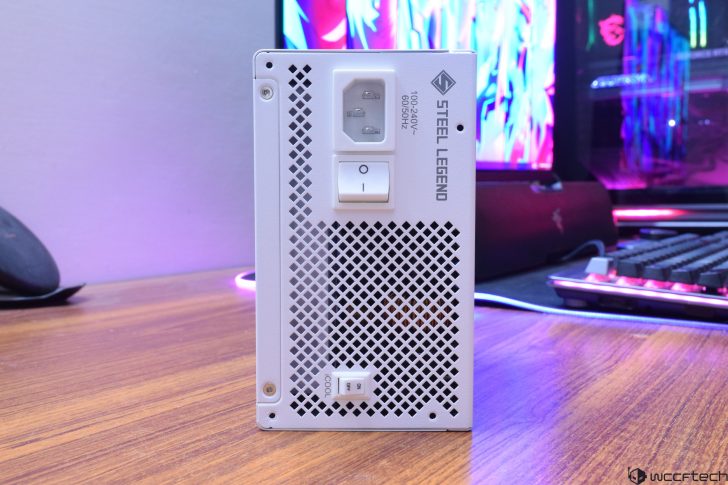 Steel Legend PC power supply on a desk with RGB setup in the background.