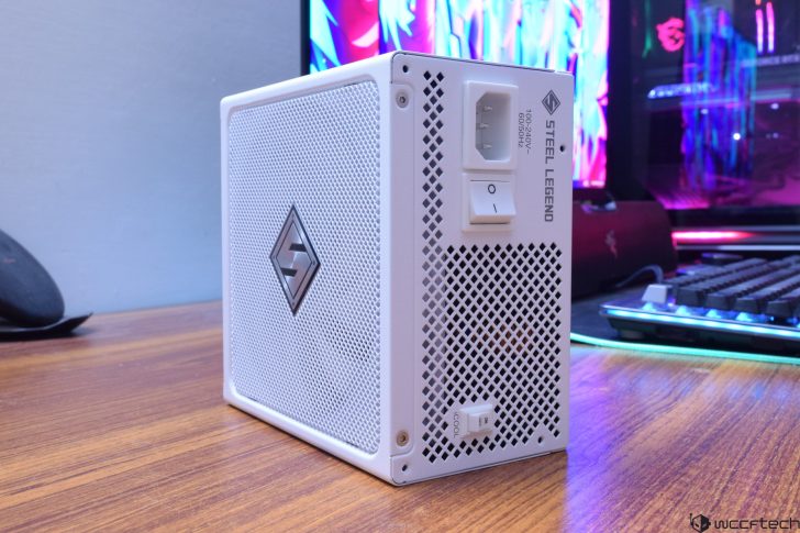 White Steel Legend power supply unit on a desk setup with gaming PC and colorful background.