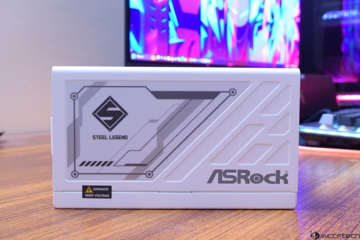 ASRock Steel Legend PC component on desk with colorful screen in background.