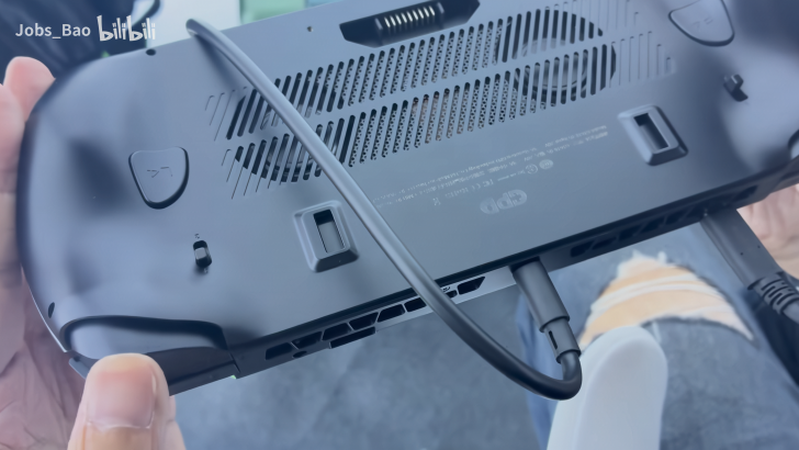 Hand holding a device with vents and cables attached, offering a tech connectivity solution.