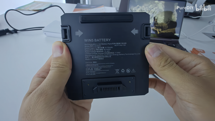 Hands holding a WIN5 rechargeable Li-ion battery with specifications.
