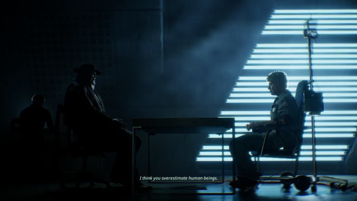 A man in a dark room sits at a table facing another person with text “I think you overestimate human beings” displayed below.