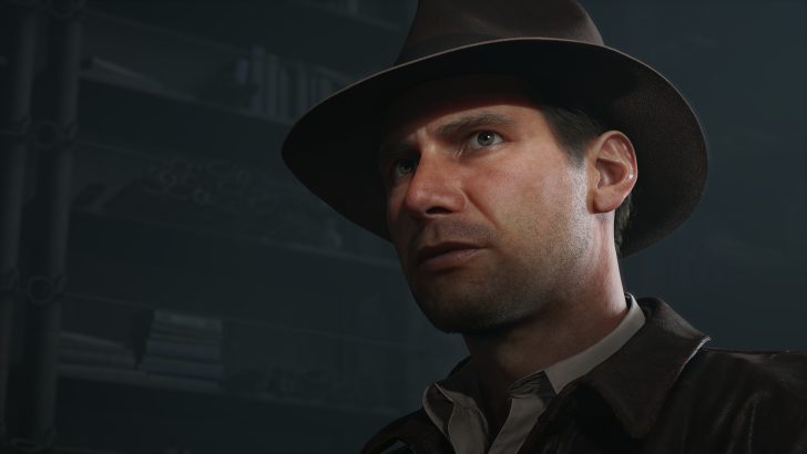 Man in a fedora and leather jacket stares intently, set against a dimly lit background.