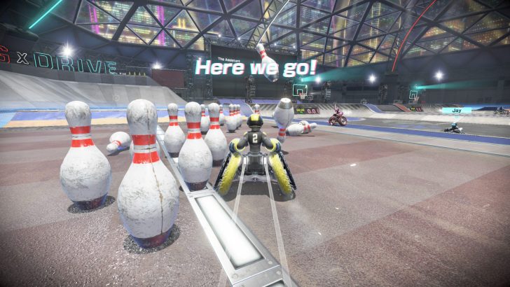 Wheelchair racer tackles a giant bowling lane, aiming for pins under Here we go! sign.