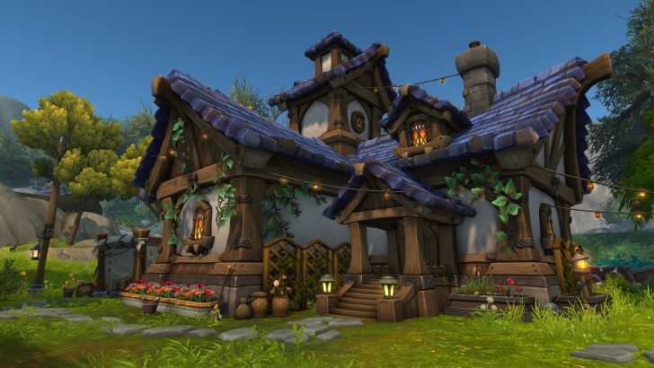 Charming fairy-tale cottage with blue roof surrounded by trees and vibrant flowers under a clear sky.