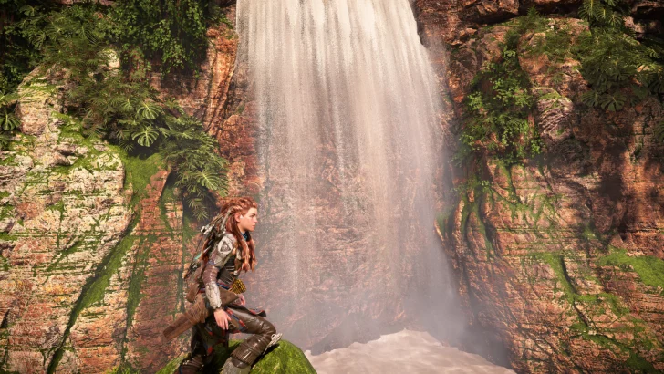 Character in armor kneels by majestic waterfall, lush greenery surrounds rocky cliffs.