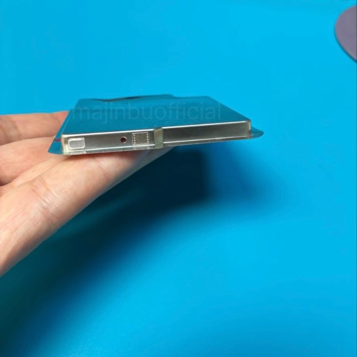 Person holding a sleek smartphone prototype with metal edges on a blue background.