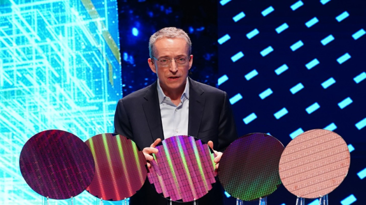 Person presenting colorful semiconductor wafers on stage at technology event.