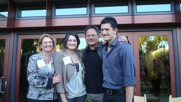 Four people smiling outside a building with large windows.
